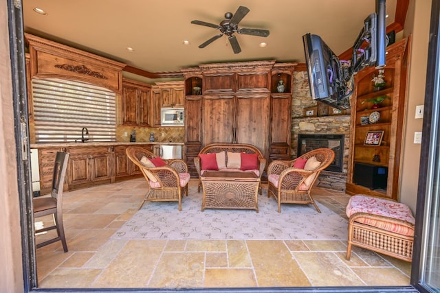 living area featuring a fireplace, a ceiling fan, recessed lighting, and stone tile floors