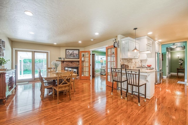 dining room featuring recessed lighting, a textured ceiling, light wood-style flooring, and baseboards