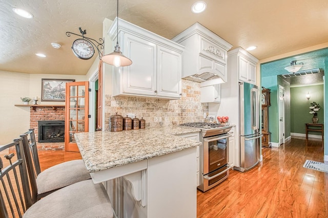 kitchen featuring a breakfast bar, recessed lighting, white cabinetry, light wood-style flooring, and appliances with stainless steel finishes