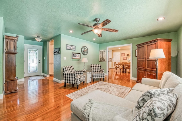 living area with baseboards, light wood-style floors, recessed lighting, a textured ceiling, and a ceiling fan
