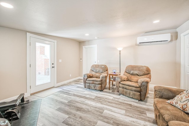 living area with recessed lighting, baseboards, a wall unit AC, and light wood-type flooring