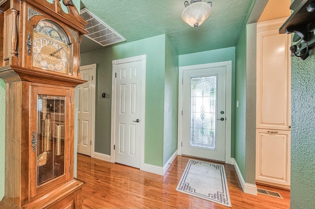 foyer entrance featuring baseboards, visible vents, and light wood-style flooring