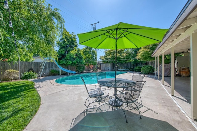 view of pool featuring a patio, a fenced backyard, a fenced in pool, a diving board, and a water slide