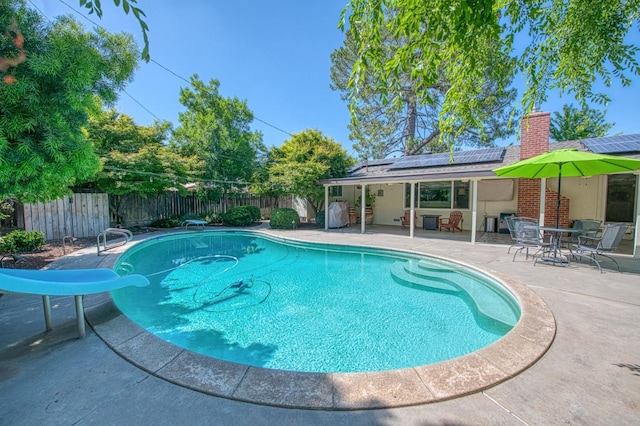 view of swimming pool with a patio, a fenced backyard, a fenced in pool, a diving board, and a water slide