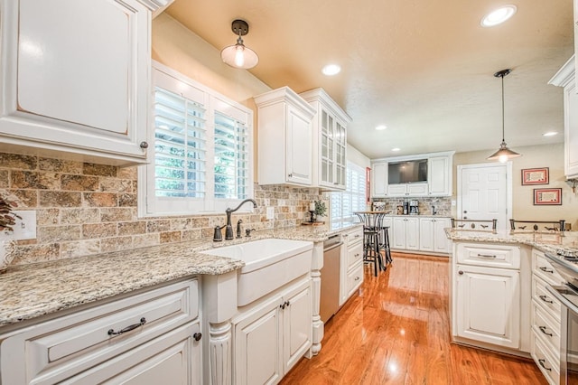 kitchen with a sink, white cabinets, a wealth of natural light, and decorative backsplash