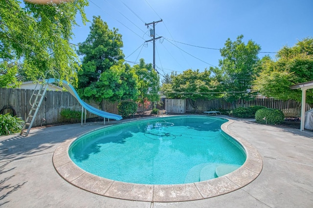 view of swimming pool with a diving board, a patio area, a fenced in pool, a fenced backyard, and a water slide