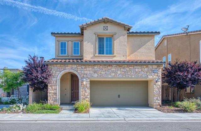 mediterranean / spanish-style home featuring a garage, fence, a tile roof, and stone siding
