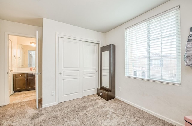 unfurnished bedroom with baseboards, a closet, and light colored carpet