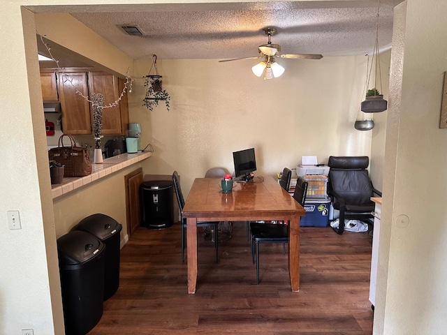 dining room featuring a textured ceiling, visible vents, and dark wood-type flooring