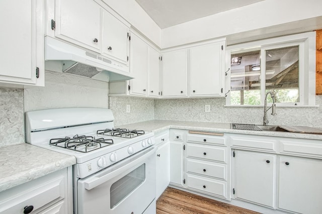 kitchen featuring decorative backsplash, a sink, light countertops, white gas range oven, and under cabinet range hood