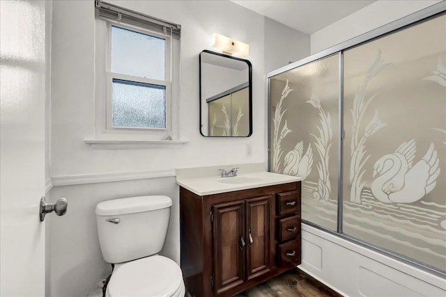 full bath featuring vanity, combined bath / shower with glass door, wood finished floors, and toilet