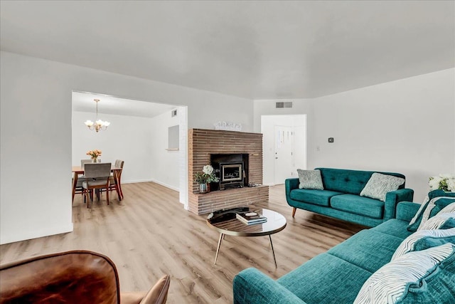living area featuring an inviting chandelier, baseboards, wood finished floors, and visible vents