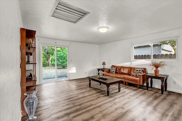 living room featuring baseboards, a textured ceiling, and wood finished floors