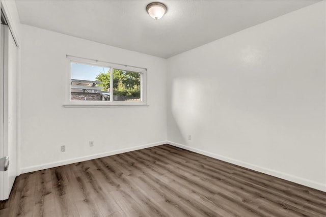 unfurnished bedroom with baseboards, wood finished floors, and a closet