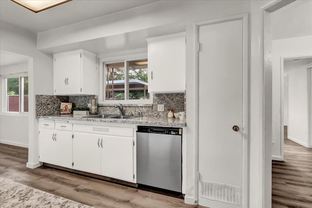 kitchen featuring decorative backsplash, stainless steel dishwasher, light wood-type flooring, a sink, and white cabinetry