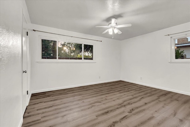 unfurnished room featuring a healthy amount of sunlight, baseboards, ceiling fan, and wood finished floors