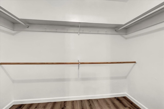 walk in closet with dark wood-style flooring