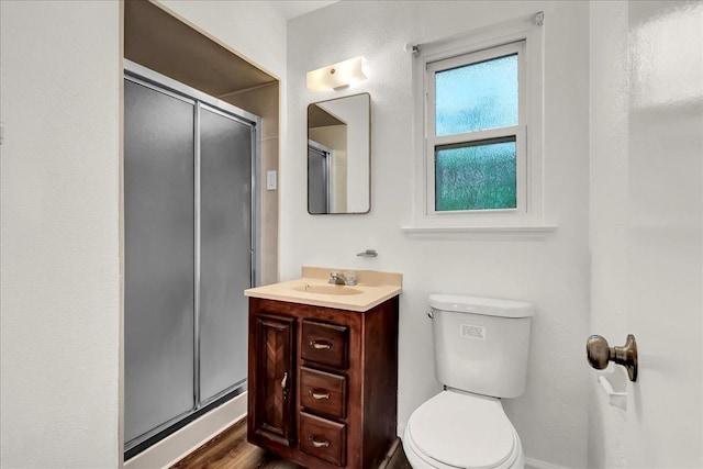 bathroom featuring vanity, a stall shower, toilet, and wood finished floors