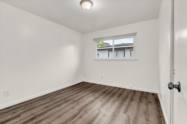 spare room with baseboards and wood finished floors
