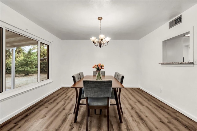 dining area featuring an inviting chandelier, baseboards, wood finished floors, and visible vents