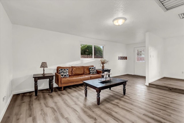 living area with baseboards, wood finished floors, and visible vents