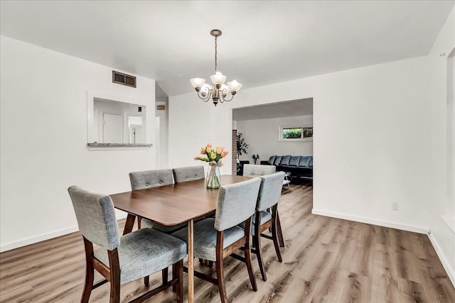 dining room with baseboards, a notable chandelier, light wood-type flooring, and visible vents