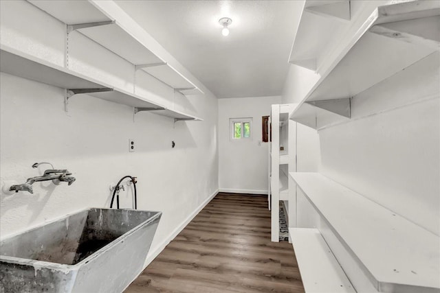 clothes washing area with baseboards, a sink, and wood finished floors