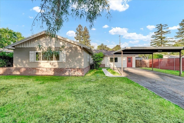 ranch-style home with driveway, brick siding, fence, a front lawn, and stucco siding
