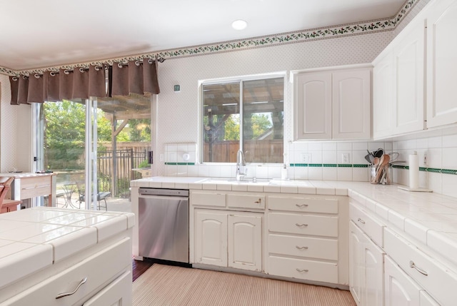 kitchen featuring a sink, plenty of natural light, tile countertops, and dishwasher