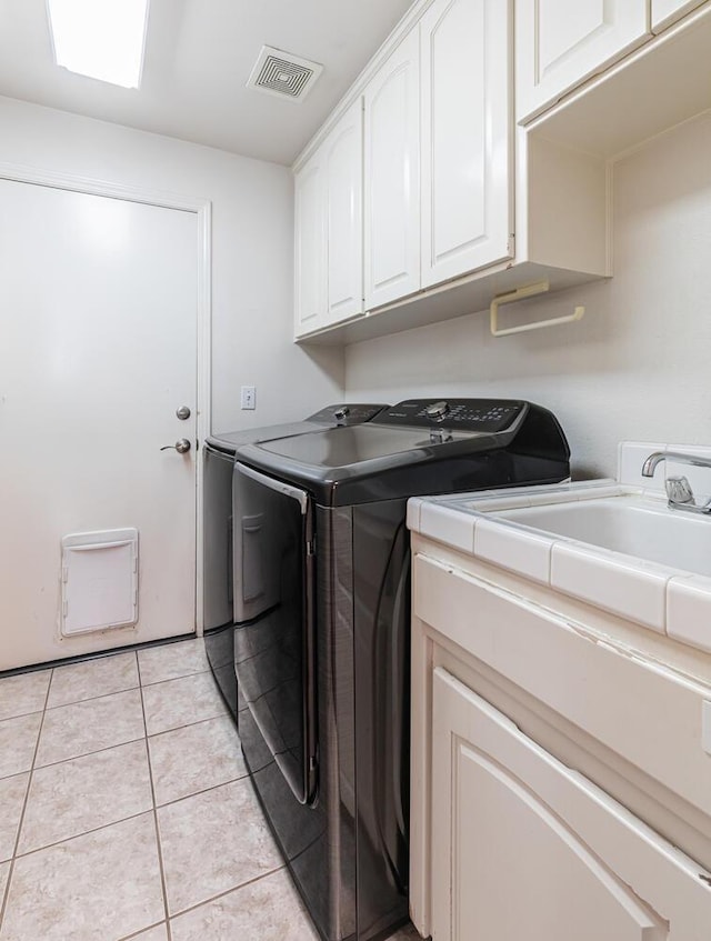 laundry room with visible vents, light tile patterned flooring, washer and clothes dryer, a sink, and cabinet space