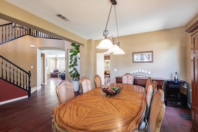 dining room featuring visible vents, wood finished floors, beverage cooler, stairway, and arched walkways