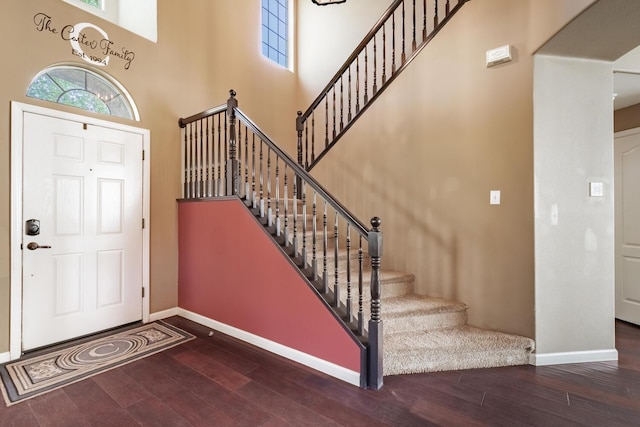 foyer entrance featuring stairway, baseboards, wood finished floors, and a high ceiling