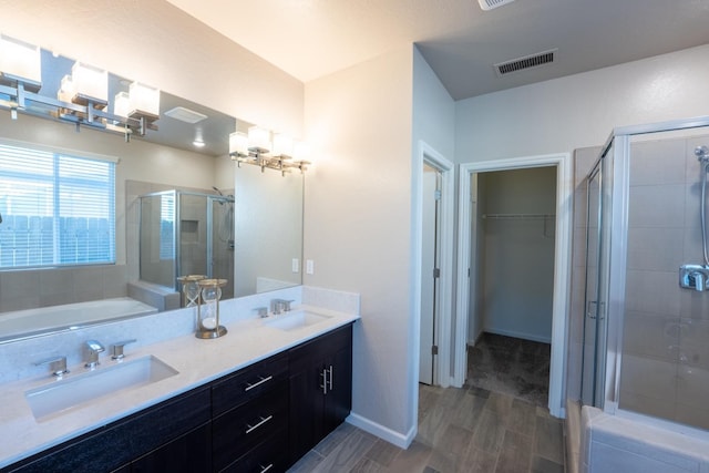 bathroom featuring visible vents, a sink, wood finish floors, and a shower stall