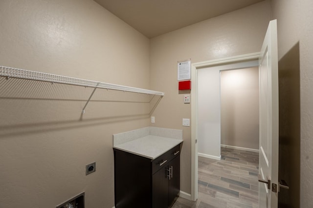 laundry room featuring electric dryer hookup, cabinet space, and baseboards