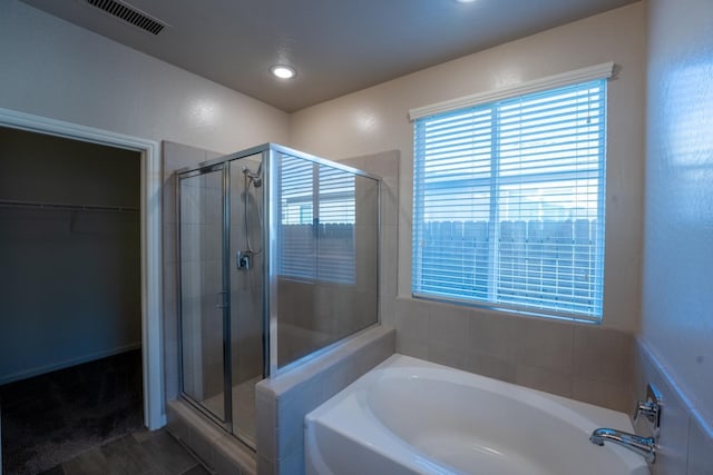 full bathroom with a spacious closet, a shower stall, a bath, and visible vents