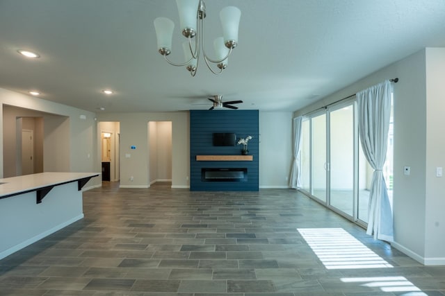 unfurnished living room with a large fireplace, wood finished floors, baseboards, ceiling fan with notable chandelier, and recessed lighting