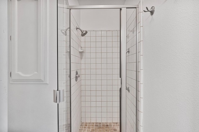 full bath featuring a textured wall and a stall shower