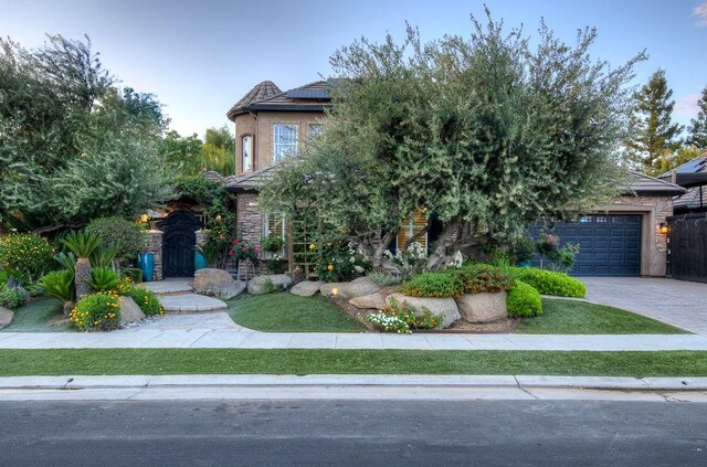 71 Omaha Ave, Clovis, CA 93619 - obstructed view of property featuring roof mounted solar panels, stone siding, a garage, and driveway