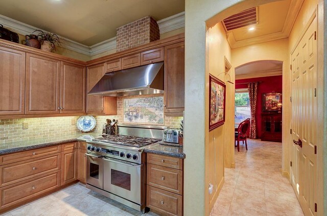 71 Omaha Ave, Clovis, CA 93619 - kitchen featuring range with two ovens, under cabinet range hood, ornamental molding, arched walkways, and tasteful backsplash