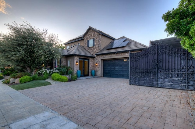 71 Omaha Ave, Clovis, CA 93619 - view of front of property featuring stone siding, an attached garage, decorative driveway, solar panels, and a gate