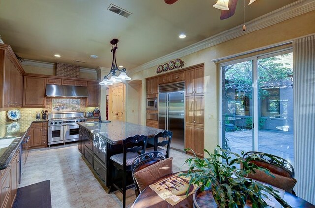 71 Omaha Ave, Clovis, CA 93619 - kitchen with built in appliances, under cabinet range hood, dark stone counters, tasteful backsplash, and a ceiling fan
