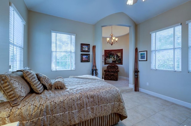 bedroom featuring baseboards, arched walkways, light tile patterned floors, and a chandelier