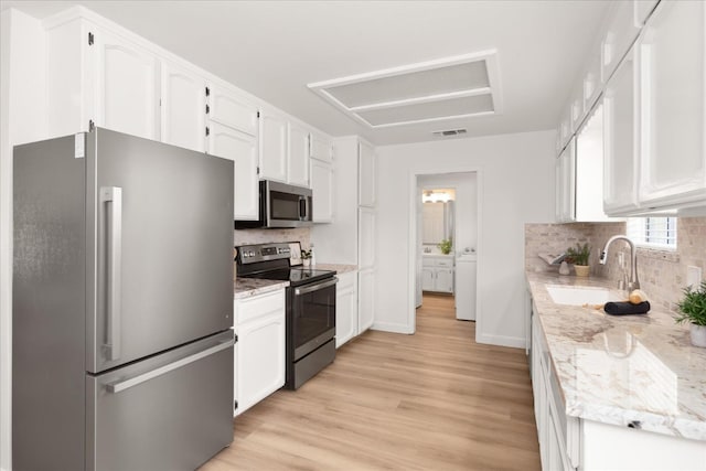42968 Ranger Circle Dr, Coarsegold, CA 93614 - kitchen with visible vents, a sink, white cabinets, stainless steel appliances, and washer and clothes dryer