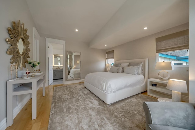 bedroom featuring recessed lighting, vaulted ceiling, wood finished floors, and ensuite bath