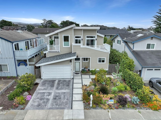 townhome / multi-family property with driveway, a residential view, a garage, fence, and a balcony