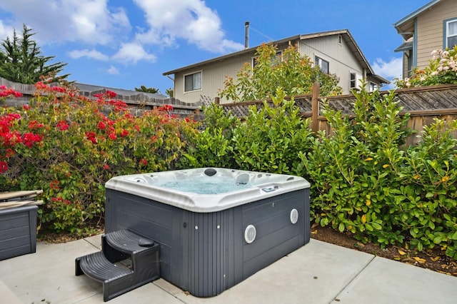 view of patio featuring a hot tub and fence