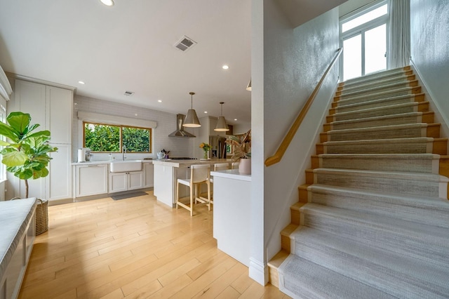 stairway with recessed lighting, wood finished floors, and visible vents