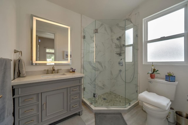full bathroom featuring toilet, a marble finish shower, and vanity