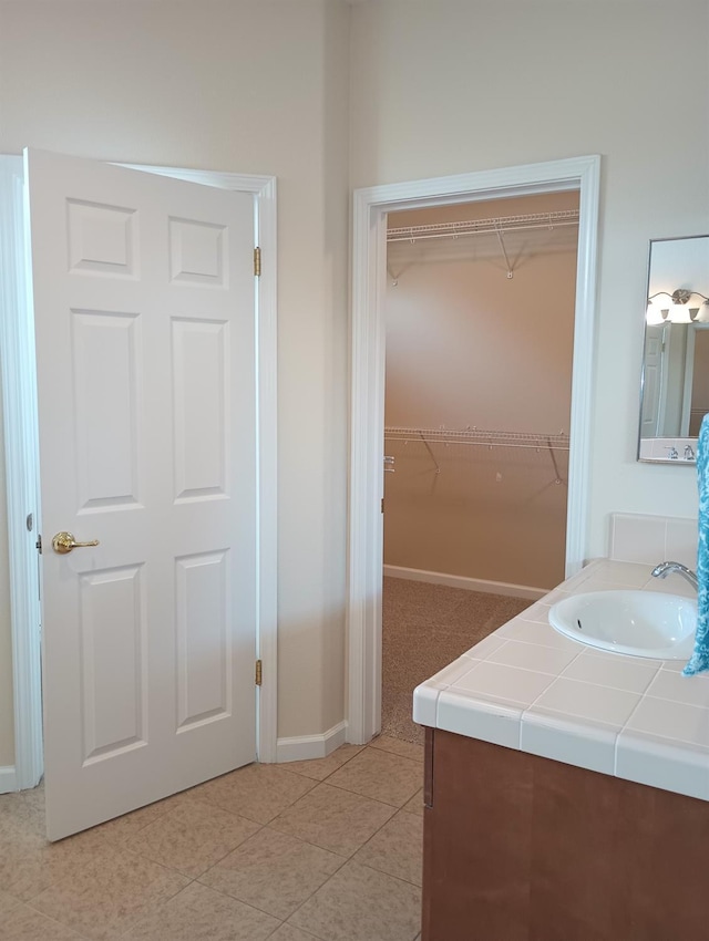 2979 Duncan Ave, Clovis, CA 93611 - bathroom featuring vanity, baseboards, a walk in closet, and tile patterned flooring