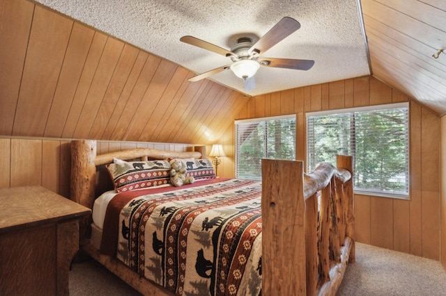 bedroom featuring a ceiling fan, a textured ceiling, vaulted ceiling, wood walls, and carpet